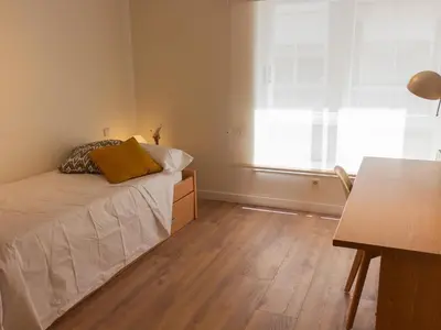 a bedroom with a bed and a desk and a window at Housingcoruña sada playa in Sada
