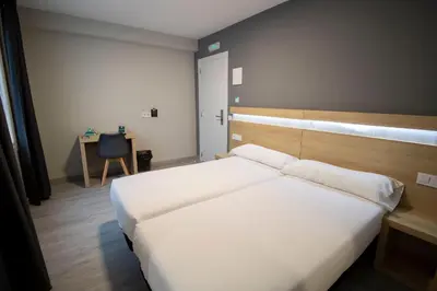 a bedroom with a large white bed and a desk at Alda Catedral in Santiago de Compostela