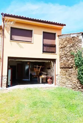 a house with a garage and a stone wall at Casa das Pozas 2 in Monforte de Lemos
