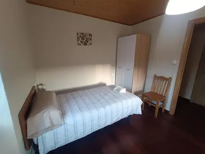 a bedroom with a bed and a chair and a cabinet at CASA ISAURA DE PENA Camino Primitivo in Pacio