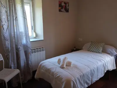 a bedroom with a bed with white sheets and a window at CASA ISAURA DE PENA Camino Primitivo in Pacio