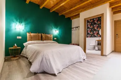 a bedroom with a large bed with a green wall at Four Rooms Hostel in Lugo
