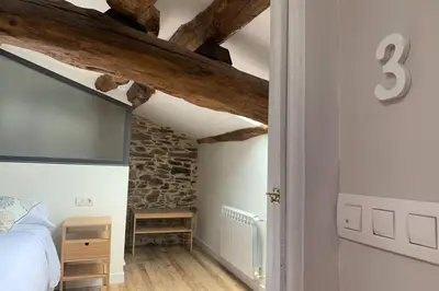 a bedroom with a bed and a stone wall at El Taller de Doña Remedios in Mondoñedo