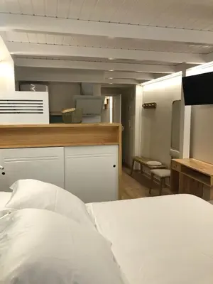 a bedroom with a white bed and a kitchen at Apartamento completamente equipado en Pontedeume. in Puentedeume