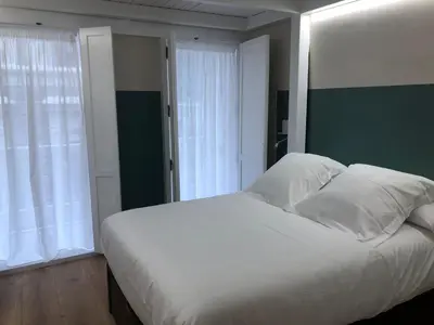 a bedroom with a white bed with a green wall at Apartamento completamente equipado en Pontedeume. in Puentedeume