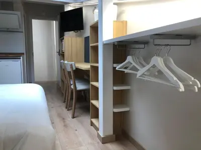 a room with a bed and a table with hangers at Apartamento completamente equipado en Pontedeume. in Puentedeume