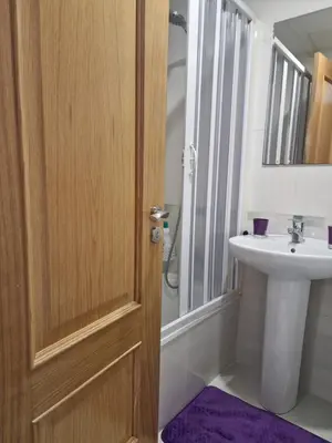 a bathroom with a sink and a wooden door at Pension Myriam O PEDROUZO in O Pedrouzo