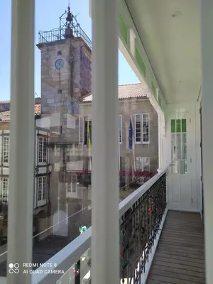 a balcony with a view of a building with a clock tower at Apartamentos Pontedeume Riadoeume in Puentedeume