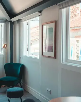 a room with a chair and two windows at Apartamentos Pontedeume Riadoeume in Puentedeume