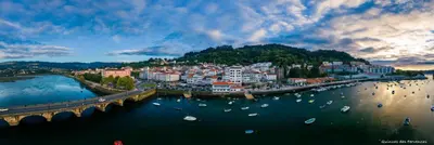 a city with a bridge and boats in the water at Apartamentos Pontedeume Riadoeume in Puentedeume