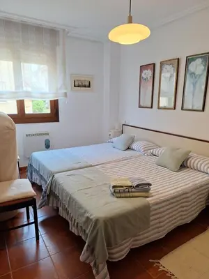 a bedroom with two beds and a chair at Apartamento Faro de Tapia in Tapia de Casariego