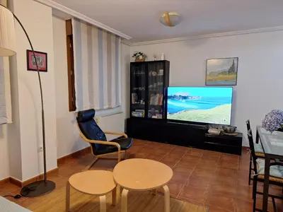 a living room with a tv and two chairs and a table at Apartamento Faro de Tapia in Tapia de Casariego