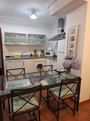 a kitchen with a glass table and two chairs at Apartamento Faro de Tapia in Tapia de Casariego