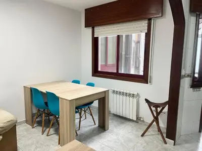 a dining room table with blue chairs and a window at Apartamento Bralo in Padrón