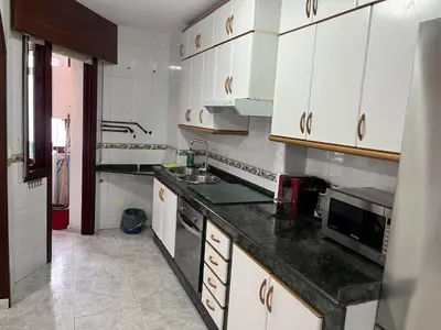 a kitchen with white cabinets and a black counter top at Apartamento Bralo in Padrón
