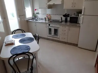 a kitchen with two tables and a white refrigerator at Apartamento Puerto de Foz in Foz
