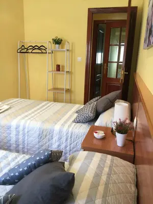 a bedroom with two beds and a wooden table at Apartamento Puerto de Foz in Foz