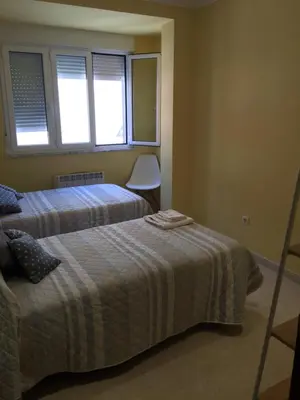 a bedroom with two beds and two windows at Apartamento Puerto de Foz in Foz