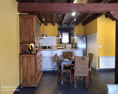 a kitchen with a table and chairs and a counter at La obra de Joaquin, tu rincón en el Bierzo alto in Folgoso de la Ribera