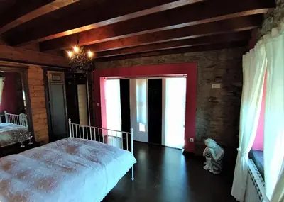 a bedroom with a bed and a red wall at La obra de Joaquin, tu rincón en el Bierzo alto in Folgoso de la Ribera