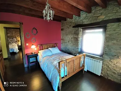 a bedroom with a bed and a stone wall at La obra de Joaquin, tu rincón en el Bierzo alto in Folgoso de la Ribera
