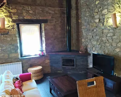a living room with a stone wall with a fireplace at La obra de Joaquin, tu rincón en el Bierzo alto in Folgoso de la Ribera