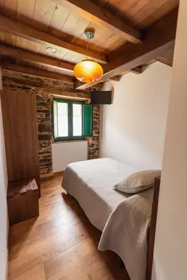 a bedroom with a bed in a room with wooden ceilings at Apartamentos Rurales Casa Llongo in Coaña