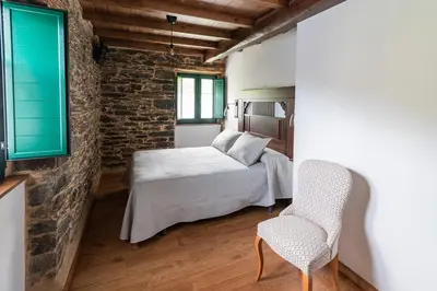 a bedroom with a bed and a chair at Apartamentos Rurales Casa Llongo in Coaña