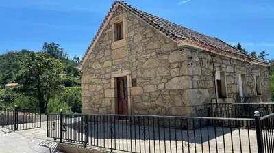 an old stone building with a fence in front of it at Casa 2 Gallos in Ourense