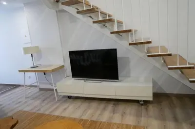 a living room with a tv on a dresser and stairs at Apartamentos Antares 3 in Milladoiro