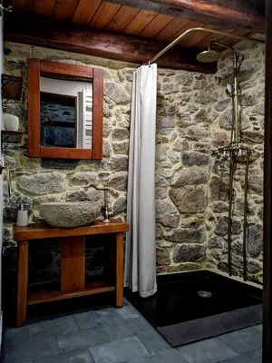 a bathroom with a sink and a stone wall at El Cuarto in Suarbol