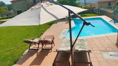 an umbrella and two chairs next to a swimming pool at Eirixo in Valga
