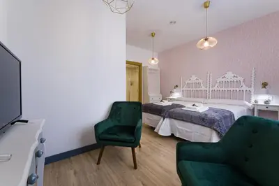 a bedroom with a bed and a green chair at Pensión Ferradura in Melide