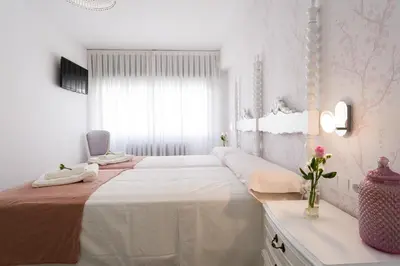 a white bedroom with a large bed and a window at Pensión Ferradura in Melide