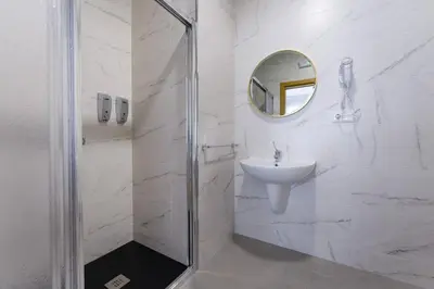 a white bathroom with a sink and a mirror at Pensión Ferradura in Melide