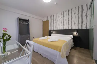 a bedroom with a large bed with a yellow blanket at Pensión Ferradura in Melide