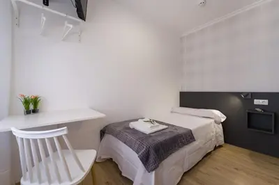 a small bedroom with a bed and a chair at Pensión Ferradura in Melide