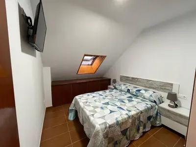 a bedroom with a bed and a tv on a wall at Altamira in Caldas de Reis