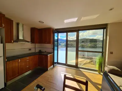 a kitchen with a large window with a view of the water at APARTAMENTOS VIVE in Viveiro