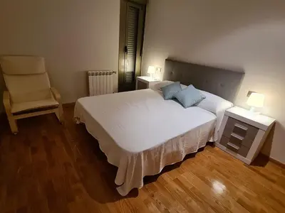 a bedroom with a large white bed and a chair at APARTAMENTOS VIVE in Viveiro