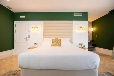 a bedroom with a large white bed with green walls at Hotel Boutique Casa do Estanco in Quiroga