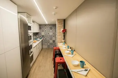 a kitchen with long tables and red stools at THOSTEL in Santiago de Compostela