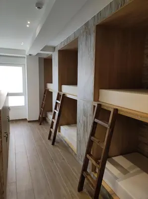 a room with three bunk beds and two chairs at THOSTEL in Santiago de Compostela