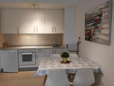 a kitchen with a table with white cabinets and white chairs at San Ciprian Marinero by I Love Norte in San Ciprián