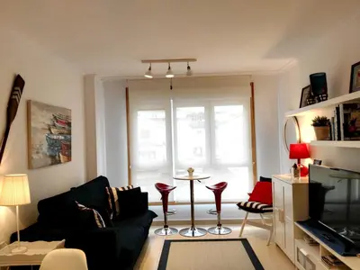 a living room with a couch and a table with red chairs at San Ciprian Marinero by I Love Norte in San Ciprián
