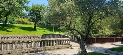 a stone fence with a tree next to a park at Apartamento Exterior Camino Inglés # a 10 min de Santiago in Sigüeiro