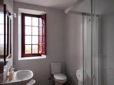 a bathroom with a toilet and a sink and a window at Albergue Abeiro do Sor in Santa María