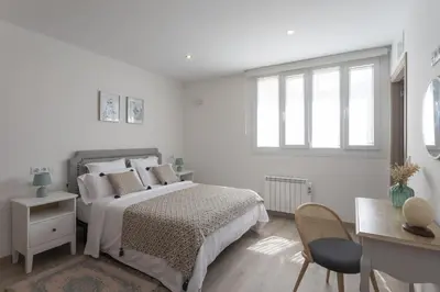 a white bedroom with a bed and a desk at Playa Ribeiría apartamento vacacional in Tapia de Casariego