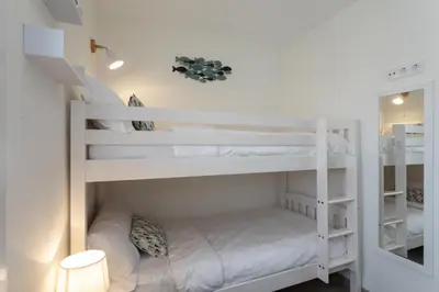 a bunk bed room with white bunk beds in it at Playa Ribeiría apartamento vacacional in Tapia de Casariego