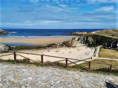 a beach with people on the sand and the ocean at Playa Ribeiría apartamento vacacional in Tapia de Casariego